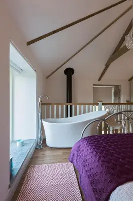 a large bathroom with a large tub and a bed at Red River Stables - Peaceful, beautiful grounds, swimming pool, central location for West Cornwall in Camborne
