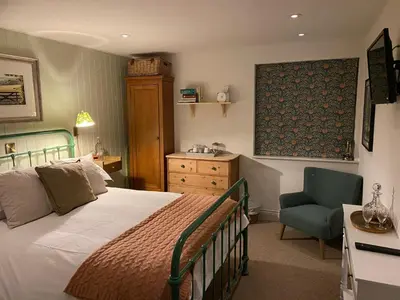 a bedroom with a large bed and a chair at The Crown Inn in Lanlivery
