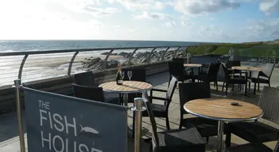 a restaurant with tables and chairs next to the beach at Stunning Two Bed Sea View Apartment with Pool & Gym in Newquay