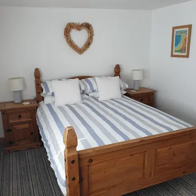 a bedroom with a wooden bed with a heart on the wall at Chynoweth Mews in Newquay