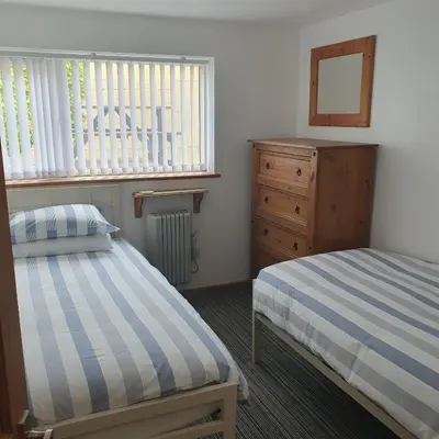 a bedroom with two beds and a dresser and a mirror at Chynoweth Mews in Newquay