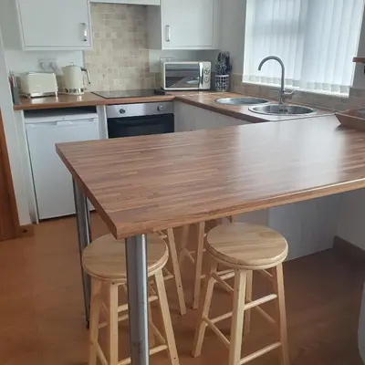 a kitchen with a wooden table and stools at Chynoweth Mews in Newquay