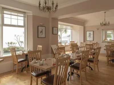 a dining room with tables and chairs and windows at Anacapri in Falmouth