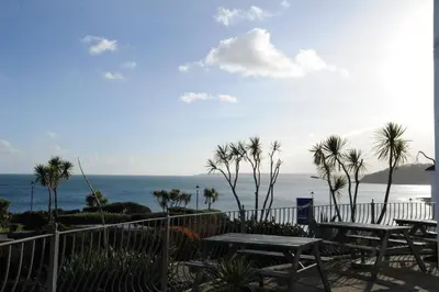a patio with tables and palm trees and the ocean at Anacapri in Falmouth