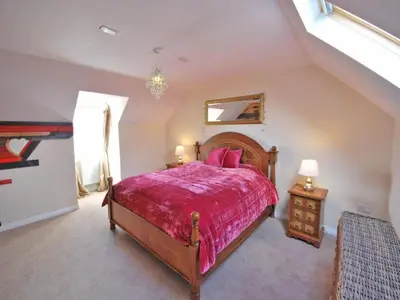 a bedroom with a large bed with a red bedspread at Luxurious House in Cornwall in Truro
