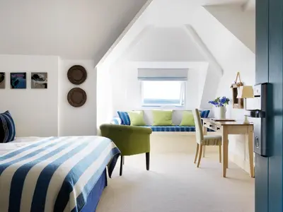 a bedroom with a bed and a desk and a chair at The St Enodoc Hotel in Wadebridge