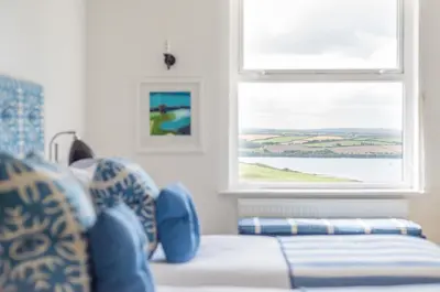 a bedroom with a bed with blue pillows and a window at The St Enodoc Hotel in Wadebridge