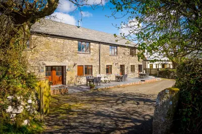 an old stone house with a patio in front of it at Cargurra Farm in Boscastle