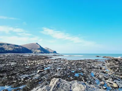 a rocky beach with mountains in the background at Cargurra Farm in Boscastle