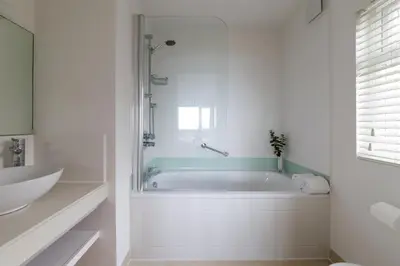 a white bathroom with a tub and a sink at Boskerris Hotel in St Ives