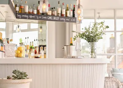 a bar with a counter with bottles of alcohol at Boskerris Hotel in St Ives