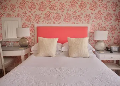 a bedroom with a white bed with a red headboard at Boskerris Hotel in St Ives