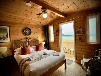 a bedroom with a bed in a wooden room with a window at Tolcarne Beach Cabins in Newquay