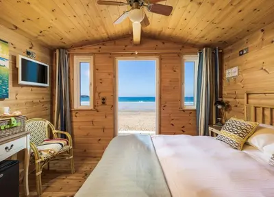 a bedroom with a bed and a view of the beach at Tolcarne Beach Cabins in Newquay