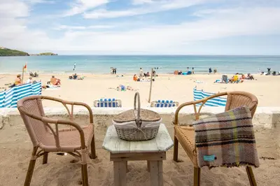 two chairs and a table on the beach at Tolcarne Beach Cabins in Newquay