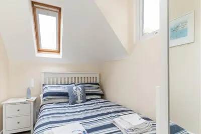 a small bedroom with a bed and two windows at Number 9 Rosemorran in St Ives