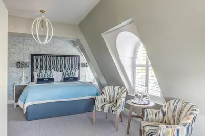 a bedroom with a blue bed and two chairs at Harbour Hotel Fowey in Fowey