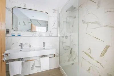a white bathroom with a sink and a mirror at Harbour Hotel Fowey in Fowey