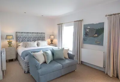 a bedroom with a bed and a blue couch at The Idle Rocks in Saint Mawes