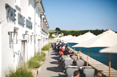 a group of people sitting under umbrellas outside a building at The Idle Rocks in Saint Mawes