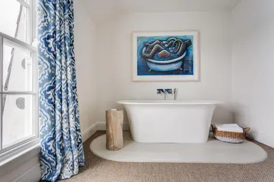 a bathroom with a white tub and a painting on the wall at The Idle Rocks in Saint Mawes