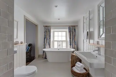 a white bathroom with a tub and a sink at The Idle Rocks in Saint Mawes
