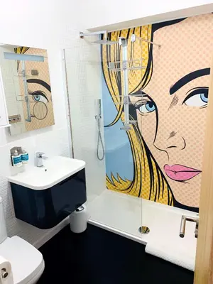 a bathroom with a shower and a painting of a woman at Porth Beach Hotel in Newquay