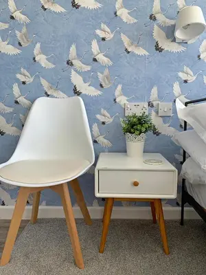 a white chair in front of a wall with a bird wallpaper at Porth Beach Hotel in Newquay