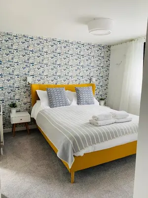 a bedroom with a large yellow bed with blue pillows at Porth Beach Hotel in Newquay