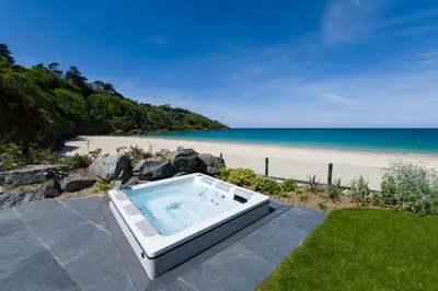 a bath tub sitting on a patio next to a beach at Carbis Bay and Spa Hotel in St Ives