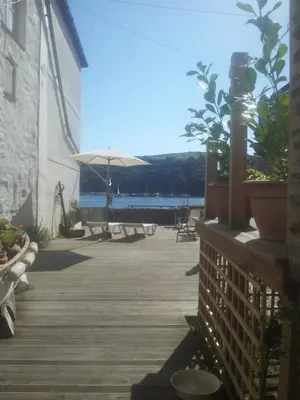 a wooden deck with potted plants and an umbrella at Reed's of Fowey in Fowey