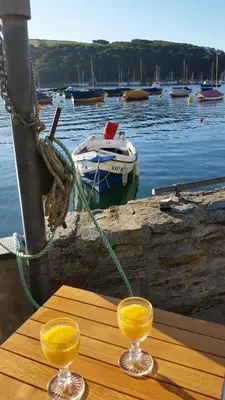 two glasses of orange juice sitting on a wooden table at Reed's of Fowey in Fowey