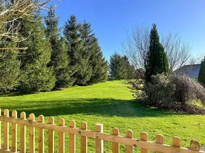 a wooden fence in front of a yard with trees at Swallows Rest in Doublebois