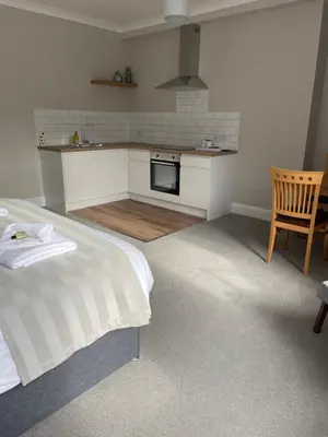 a room with a bed and a kitchen in it at Braemar in Falmouth