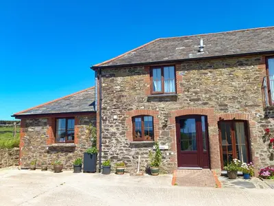 a brick house with black windows and a door at Beckaveans Stable in Jacobstow