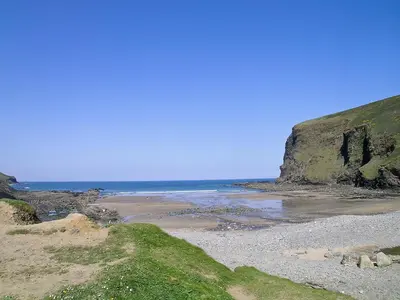 a beach with the ocean and a cliff at Beckaveans Stable in Jacobstow