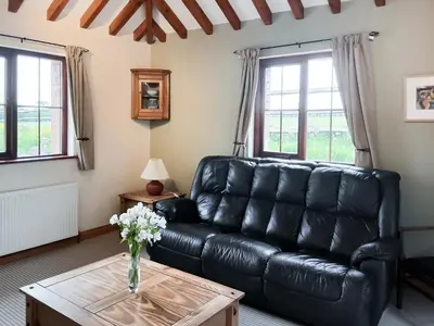 a black leather couch in a living room with a table at Beckaveans Stable in Jacobstow