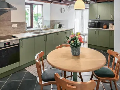 a kitchen with a table with a vase of flowers on it at Beckaveans Granary in Jacobstow