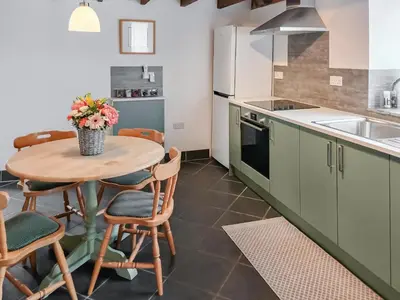 a kitchen with a table and chairs and a sink at Beckaveans Granary in Jacobstow