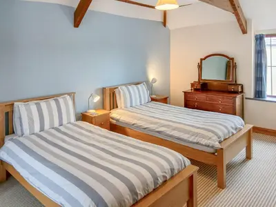 two beds in a room with a mirror and a dresser at Beckaveans Granary in Jacobstow