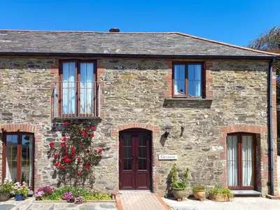 an old stone house with flowers in front of it at Beckaveans Granary in Jacobstow