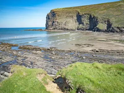 a beach with the ocean and a cliff at Beckaveans Granary in Jacobstow
