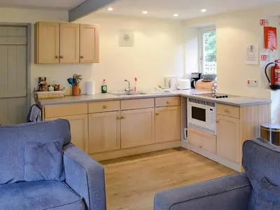 a kitchen with wooden cabinets and blue chairs in a room at Paget in Saint Kew
