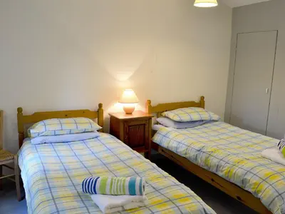 two beds in a room with a lamp on a table at Paget in Saint Kew