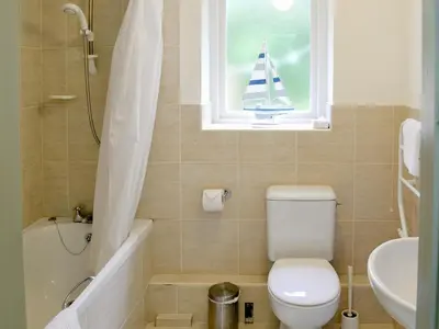 a bathroom with a toilet and a sail boat in the window at Paget in Saint Kew