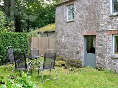 a table and chairs in front of a stone house at Paget in Saint Kew