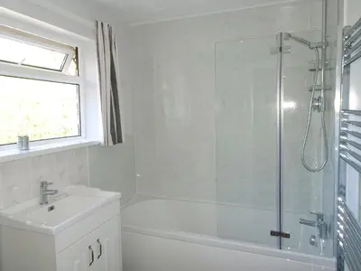a white bathroom with a shower and a sink at Tregoona in Crantock