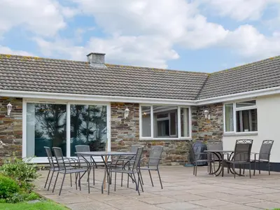 a patio with a table and chairs in front of a building at Tregoona in Crantock