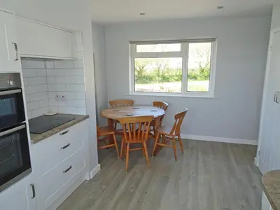 a kitchen with a table and chairs and a window at Tregoona in Crantock
