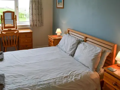 a bedroom with a bed and a desk with a mirror at Tregoona in Crantock